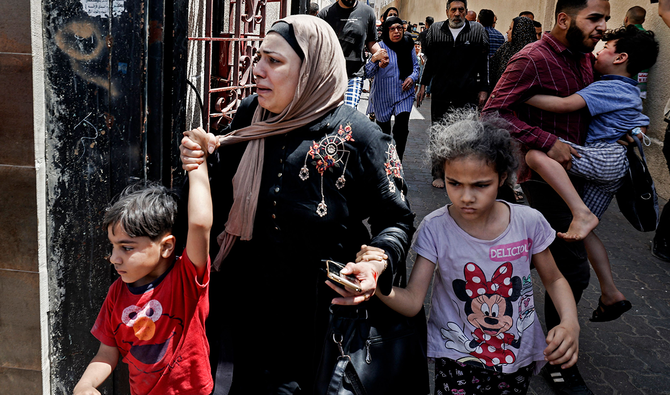 2021年5月11日、ガザ地区でイスラエルの空爆で標的となったビルから避難する市民たちの中に、泣いているパレスチナ人女性がいる。（AFP通信）