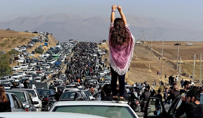 イランのマフサ・アミニさんの地元に数千人が向かう中、自動車の上に立つ女性。（AFP）