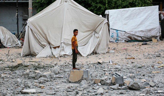 2024年6月28日、イスラエルとパレスチナの過激派組織ハマスとの間で紛争が続く中、ガザ地区中央部のデイル・アル・バラ市庁舎近くの広場で破壊された、国内避難民を収容するテントに近い瓦礫の上に立つパレスチナ人の若者。(AFP＝時事）